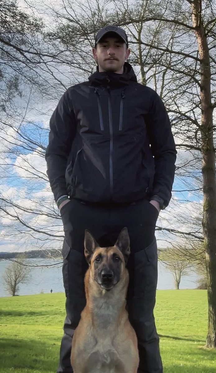 Westwood K9 Academy trainer standing with a focused Belgian Malinois by a lake